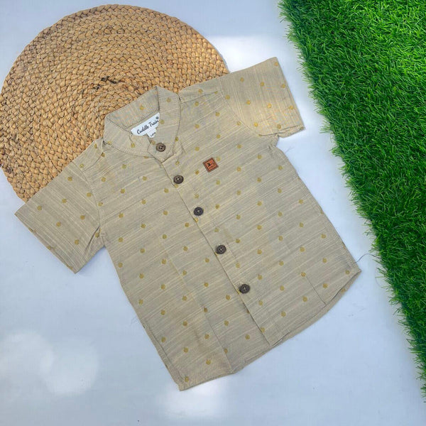 Beige shirt with brown buttons on a white surface with grass and woven mat in the background