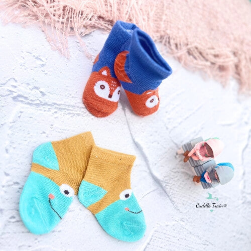 Pair of colorful baby socks with fox design on a textured surface