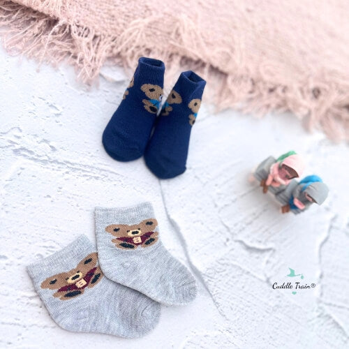 Two pairs of socks with teddy bear designs on a textured surface.