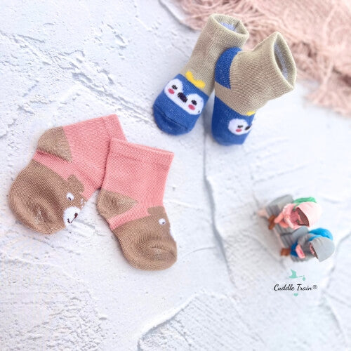 Two pairs of children's socks with animal designs on a light surface.