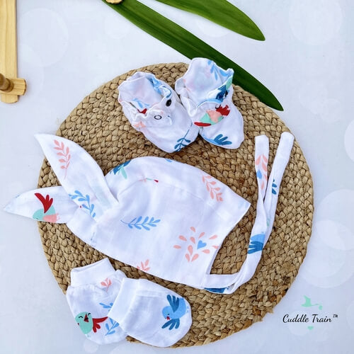 Baby accessories set including a hat, booties, and bib on a woven mat with a white background.