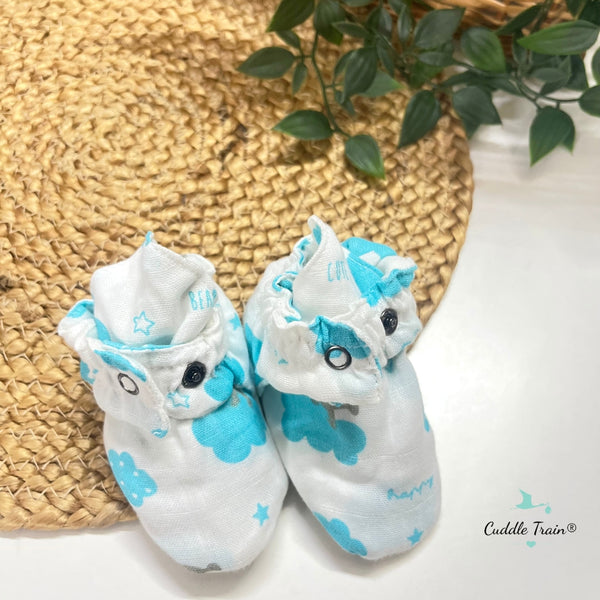 Pair of baby booties with blue and white designs on a textured surface.