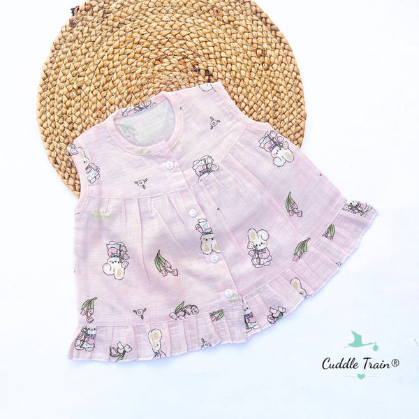 Pink baby dress with cartoon designs on a woven mat