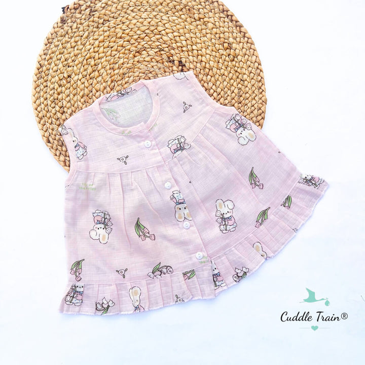 Pink baby dress with cartoon designs on a woven mat