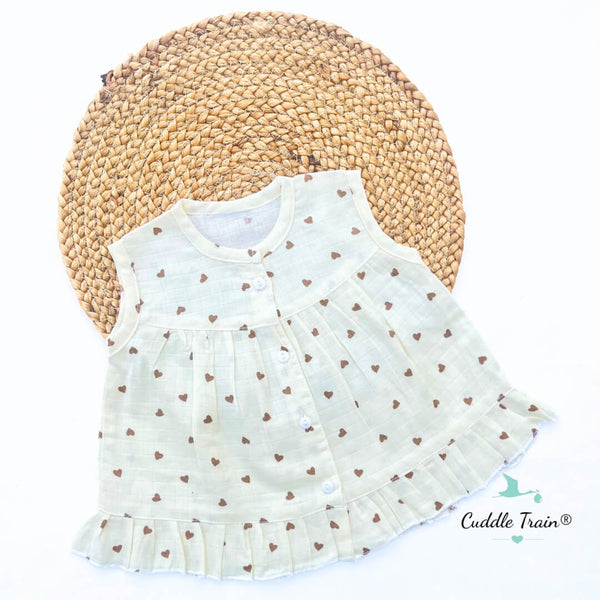White sleeveless dress with brown heart patterns on a woven mat