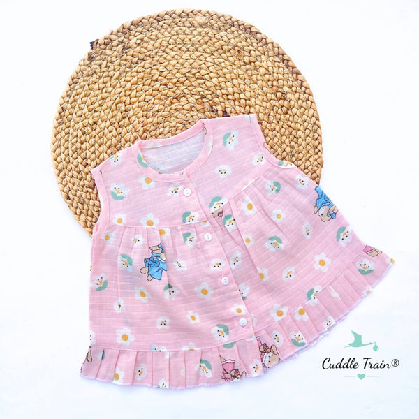 Pink children's dress with cartoon characters on a woven mat