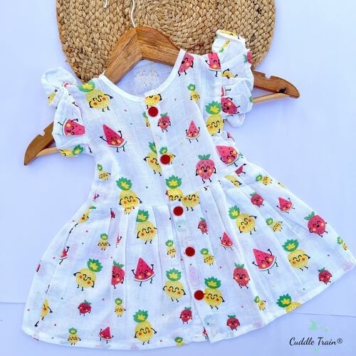 Children's dress with fruit pattern on a hanger against a white background