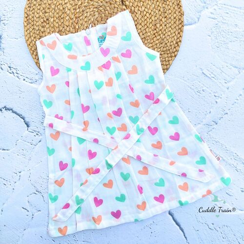 Folded baby frock with colorful heart pattern on a textured surface