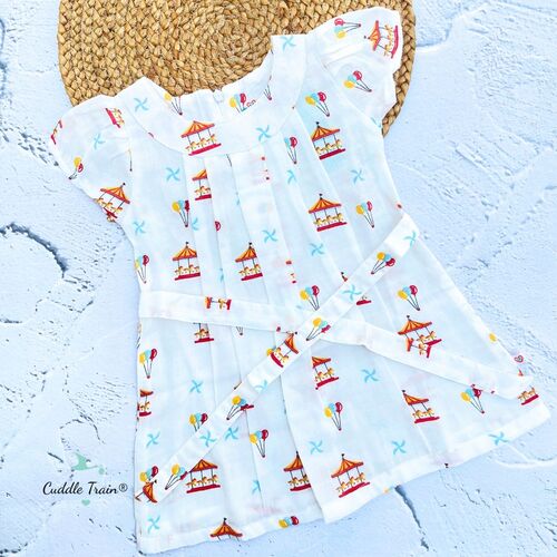 Baby frock with carousel and balloon pattern on a textured surface