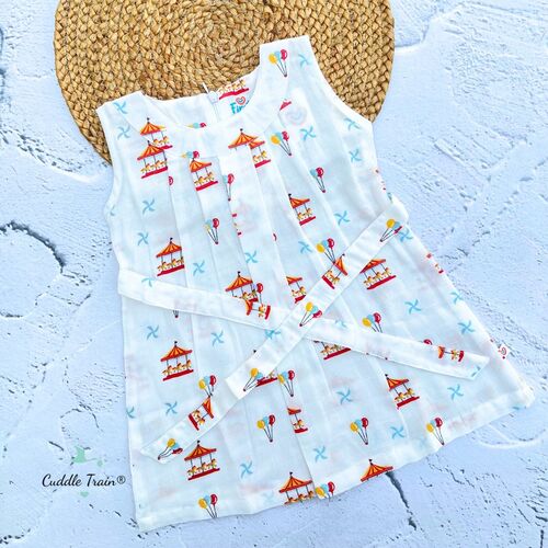White sleeveless dress with colorful carousel and balloon pattern on a textured surface.