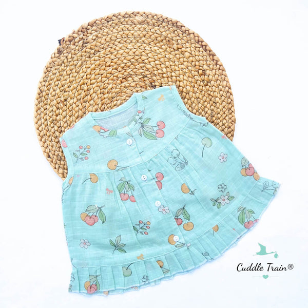 Light blue children's dress with cherry pattern on a woven mat