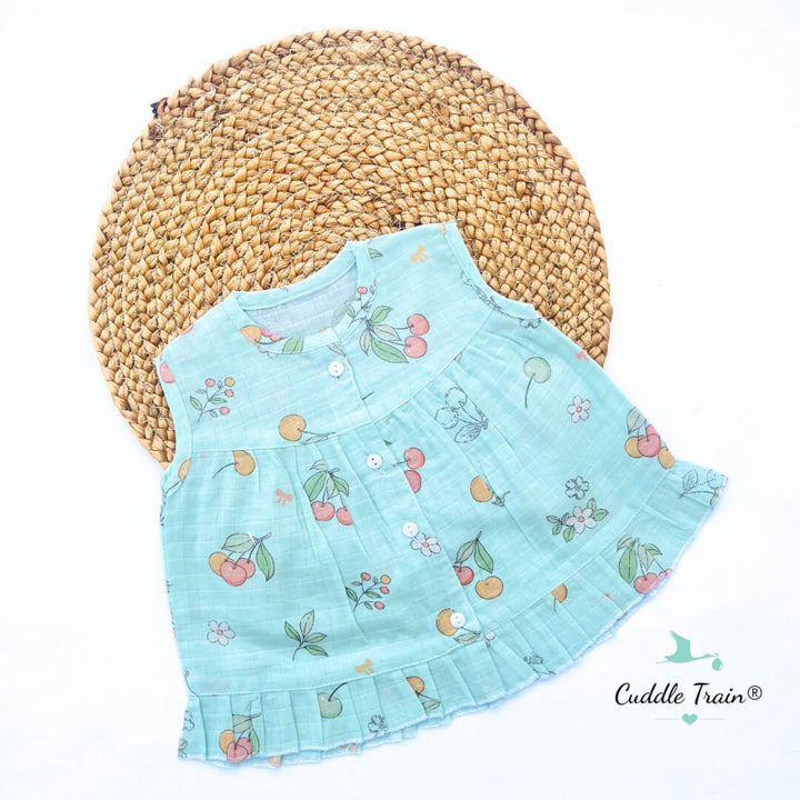 Light blue children's dress with cherry pattern on a woven mat
