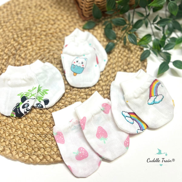 Set of baby mittens with cartoon designs on a woven mat