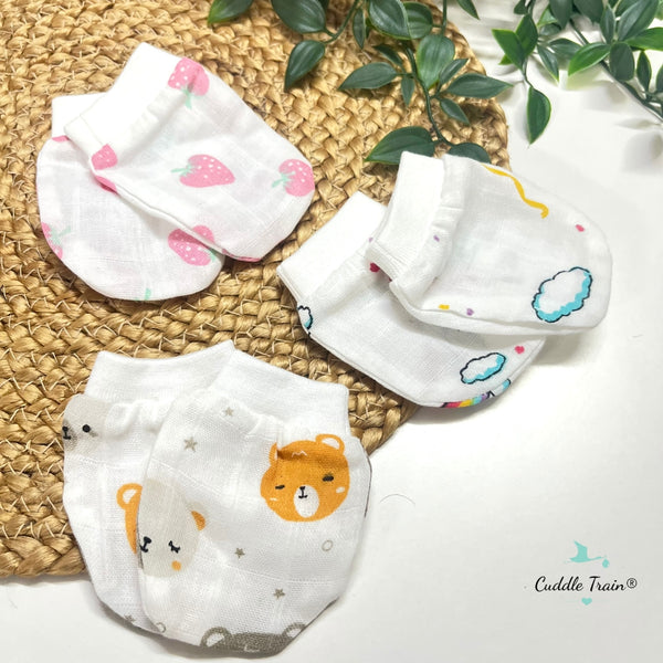 Set of baby socks with animal prints on a woven mat with a plant in the background