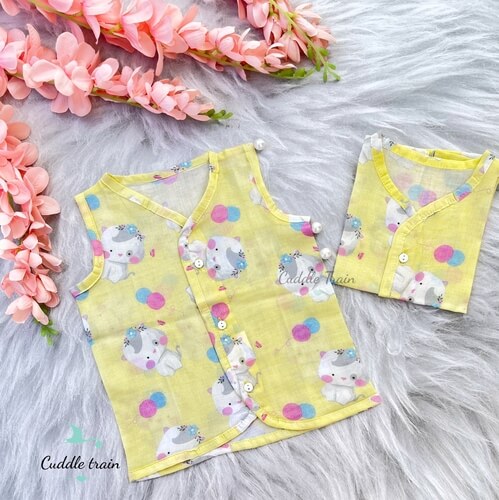 Two yellow children's vests with cartoon designs on a gray surface with pink flowers.